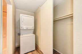 Stackable washer and dryer inside apartment with closet to the right and Hardwood Inspired Floors