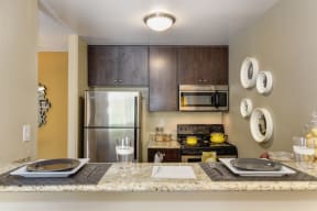 Model kitchen with granite countertops, stainless appliances and darker brown cabinetry