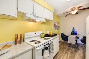 Kitchen and Dining Area with Bright Yellow Accent Walls, Hardwood Inspired Floors, Stove and White Cabinets