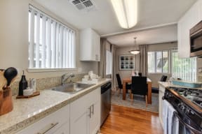 Kitchen with View of Dining Room with Wood Inspired Floor, Sink, Cupboards, Stove, Oven, Wooden Dining Room Table and Black Chairs