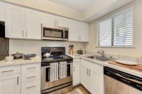 Kitchen with White Cabinets, Oven, Microwave, Window and Dishwasher