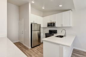 Kitchen with Dishwasher , Hardwood Inspired Floor, Oven, Microwave, White Cabinets  and Refrigerator