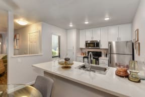 Kitchen with White Cabinents, Hardwood Inspired Floor, Dishwasher and Refrigerator
