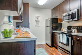 Kitchen with Stainless Steel Appliances Dishwasher, Refrigerator, Oven, and Wood Cabinets.