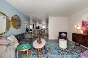 Living Room with Blue Pattern Rug, White Table, Gray Sofa, Purple Chair and Round Wall Mirrors
