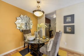 Model home dining area.  Round table with two grey chairs and rug under the table.