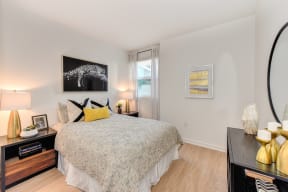 Bedroom with Hardwood Inspired Floors, White Comforter Mattress, Windows and Black Dresser