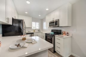 Kitchen with White Countertop, White Cabinets, Microwave and Refrigerator