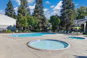 Community swimming pool and spa area.  There are lounge chairs and a table with umbrella in the distance.