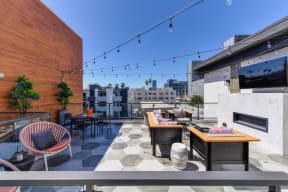 Community rooftop lounge area in the afternoon.  Area is equipped with chairs, couches, flat screen TV mounted on the wall and views of the city 