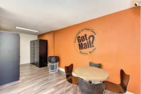Parcel Room with Hardwood Inspired Floor, Short Round Tables, Chairs, Orange Wall with "Got Pail" Painted on it