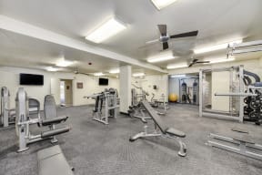 The Retreat's Fitness center with multiple weight systems & cardio equipment.  Large room that is well-lit and with ceiling fans.