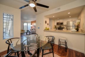 Model home dining area with ceiling fan. Open floor plan feel since you can view kitchen and living room from the dinning area. Dining table is set for four.