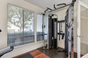 Fitness center with complete weight system.  Gym is well-lit with several windows. Walls are white and floors are hardwood inspired.