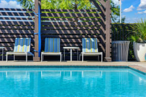 Community swimming pool area with cabanas and Lounge Chairs and side tables.