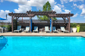 Swimming Pool Cabanas with Lounge Chairs, Lime Green Curtain and Blue Patio Umbrella in the Distance