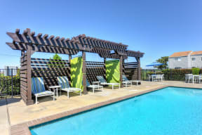 Swimming Pool Cabanas with Lounge Chairs, Lime Green Curtain and Blue Patio Umbrella in the Distance