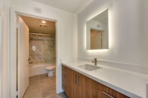 Vacant bathroom with white quartz counters and custom tiled tub/shower area 