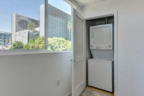 Washer and dryer inside of a closet. Door to washer/dryer is open and window shows views of outside. 
