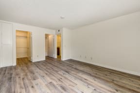 Vacant bedroom with hardwoods inspired flooring with extended closet and direct access to the bathroom 