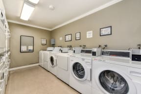 The Woods community laundry room with many washers and dryers in shared access room. 