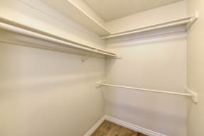 Vacant apartemt home closet which is very large.  Several clothing bars for hanging items and shelve space at the top. 
