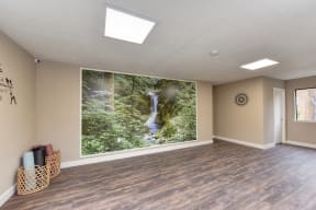 Community Yoga Studio with Hardwood Inspired Floor, Ceiling Lights, Large Window and Wicker Basket with Yoga Mats 