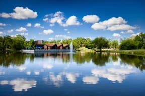 large pond with a water fountain reflecting the blue sky near The Bennington Apartments in Bensenville