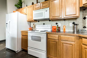 kitchen with wood cabinets and white appliances at East End Lofts apartment homes in Houston