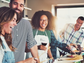 a group of young people cooking together and laughing