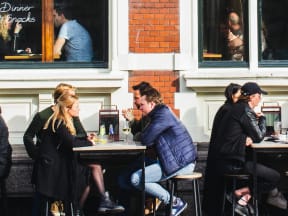 groups of tables dining during a brisk day at a few sidewalk tables drinking wine