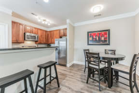 a dining area with a table and chairs and a kitchen in the background
