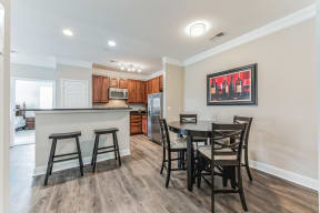 a dining area with a table and chairs and a kitchen in the background