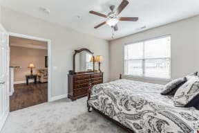 a bedroom with a large window and a ceiling fan