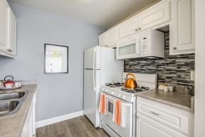Kitchen with appliances and tile backsplash  l Emerald Hills Apartments in Monterey Park