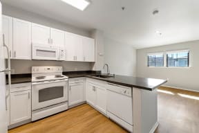 a kitchen with white cabinets and a black counter top at K Street Flats, California, 94704