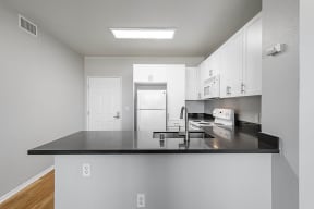 a kitchen with white cabinets and a black counter top at K Street Flats, Berkeley California 