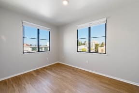 a bedroom with two windows and a hardwood floor at K Street Flats, Berkeley 