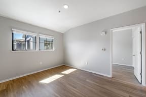 a bedroom with a hardwood floor and two windows at K Street Flats, Berkeley, CA