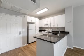 a kitchen with white cabinets and a black counter top at K Street Flats, Berkeley, CA