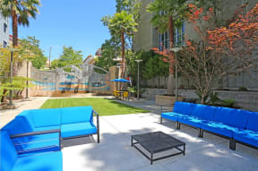a patio with blue couches and a coffee table in front of a building with a slide at K Street Flats, Berkeley, CA