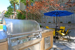 a barbecue grill with a table and chairs in the background at K Street Flats, Berkeley