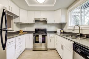 Apartments for Rent Sacramento - Sixty58 - Modern Kitchen with White Cabinets, Stainless Steel Appliances, and Wood-Style Flooring