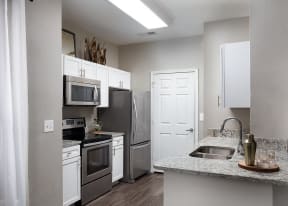 City Place at Westport - Modern Kitchen With Granite Countertops, Stainless Steel Appliances, and Wood Floors