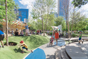 Klyde Warren Park with children and adults playing on a sunny day