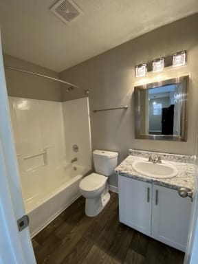 North Charleston SC Apartments for Rent - The Retreat at Palm Pointe Apartments Bathroom With Bath Tub Attached to Shower, Lit Mirror, and Hardwood Flooring