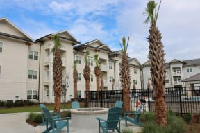 Apartments for Rent in North Charleston - Duke of Charleston - Poolside Fire Pit Surrounded By Lounge Chairs and View of Apartment Buildings