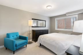 Bedroom with blue chair, dresser, mirror, lamp and bed