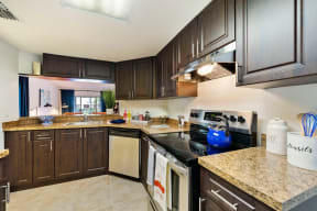 Kitchen with cabinets and stainless steel dishwasher and oven with pass-through to living room