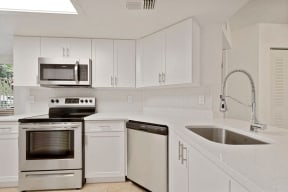 Kitchen with cabinets, sink with vegetable sprayer, stainless steel oven, microwave, and dishwasher